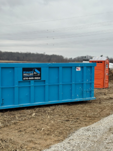 A blue roll-off dumpster from Ryan's Roll-Off Dumpsters on a construction site in Owensboro, KY.