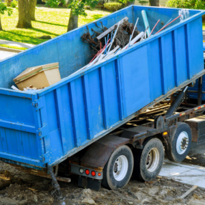 A blue roll-off dumpster on a truck, partially filled with various debris for junk removal by The Dumpster Guy in Webster, MA.