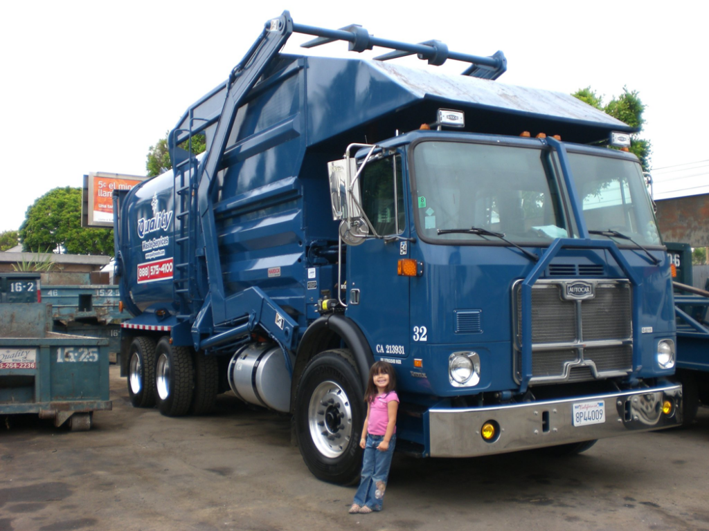 A blue roll-off truck with a large dumpster for junk removal by Quality Waste Service, Inc. in Los Angeles, CA.