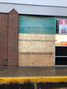 A boarded-up storefront window with plywood, showing a repair or security installation by Master Handyman, LLC in Cleveland, OH.