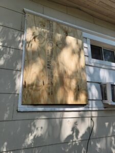 An exterior window securely boarded up, indicating repair or securing work by Friendly Handyman LLC in Wichita, KS