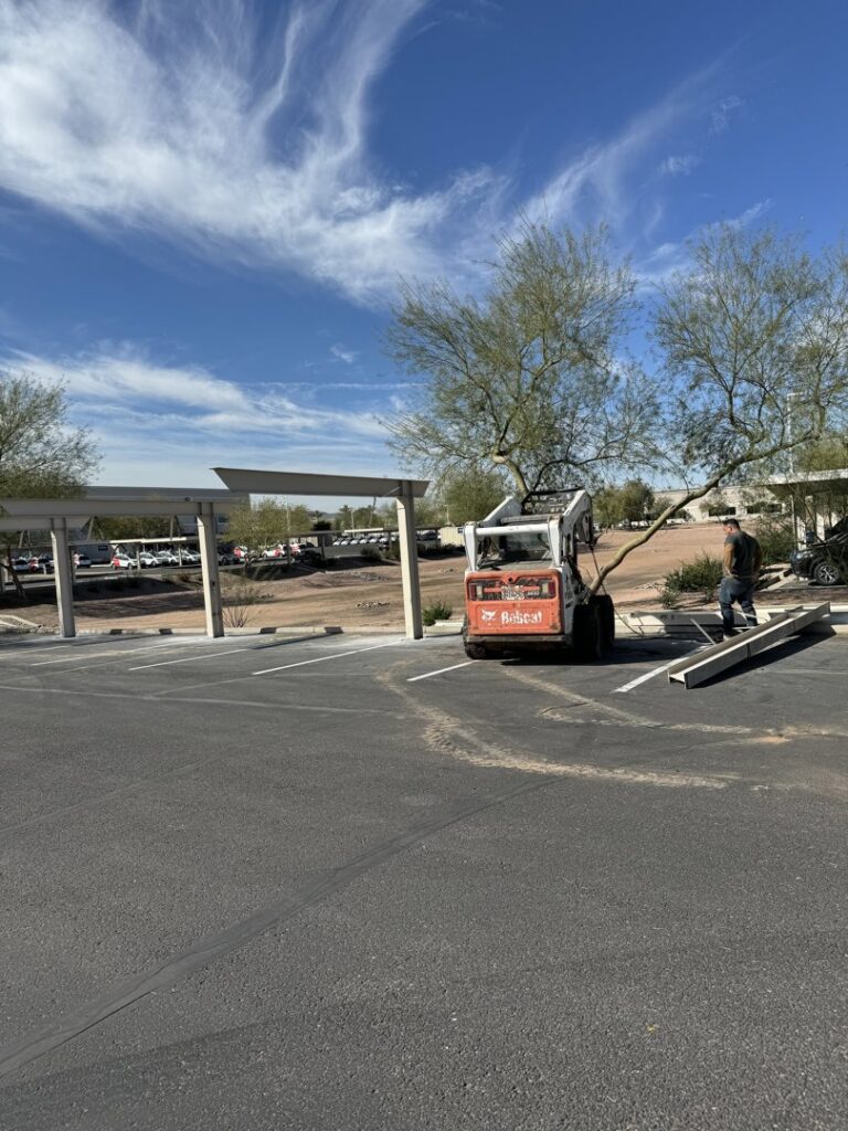 A Bobcat skid steer clearing debris in a parking lot, demonstrating site cleanup services by HAVOC Demolition in Scottsdale, AZ.