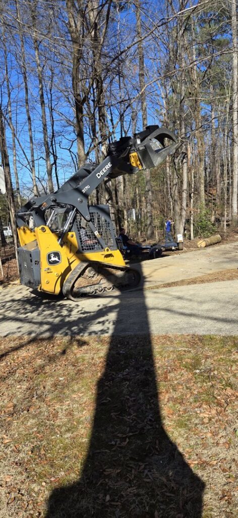 A Bobcat skid steer with a grapple attachment, used for tree service and log removal by J & K Tree Service in Robbins, NC.