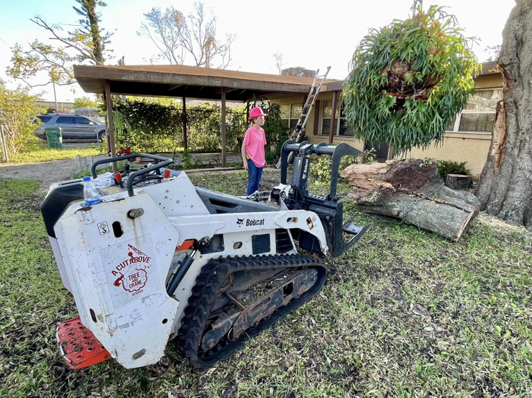 A Bobcat compact track loader with a grapple attachment used for removing a large tree trunk section by A Cut Above Tree and Crane in Carrollton, VA.