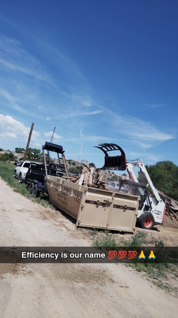 A Bobcat skid steer efficiently loading debris into a Bin Suave LLC dump trailer for junk removal in Espanola, NM.