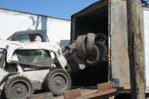 A bobcat loader efficiently loading waste tires into a semi-trailer for Tire Waste Management in Newark, NJ.