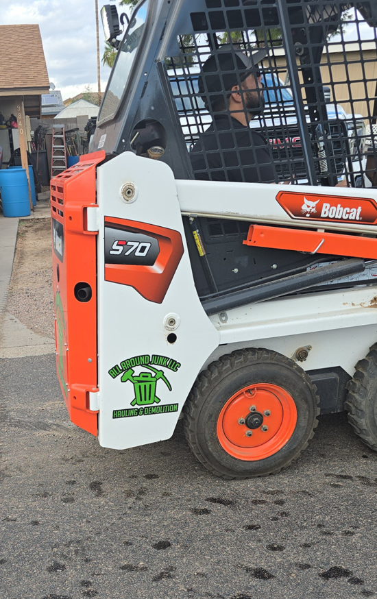 A Bobcat S70 skid-steer loader with ALL around junk, LCC branding, used for demolition and hauling in Mesa, AZ.