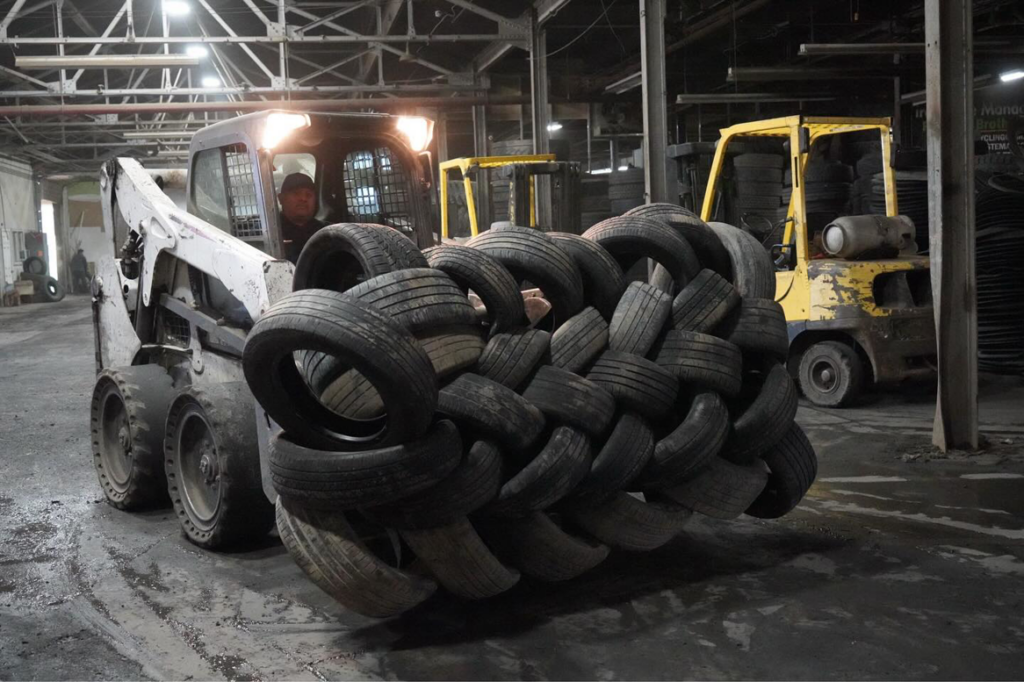 A bobcat transporting a large stack of recycled tires inside the facility for Tire Waste Management in Newark, NJ.