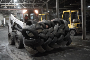 A bobcat transporting a large stack of recycled tires inside the facility for Tire Waste Management in Newark, NJ.