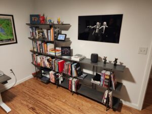 A modern bookshelf assembled and wall art hung, showcasing handyman services by Dovetails Services LLC in Derry, NH.