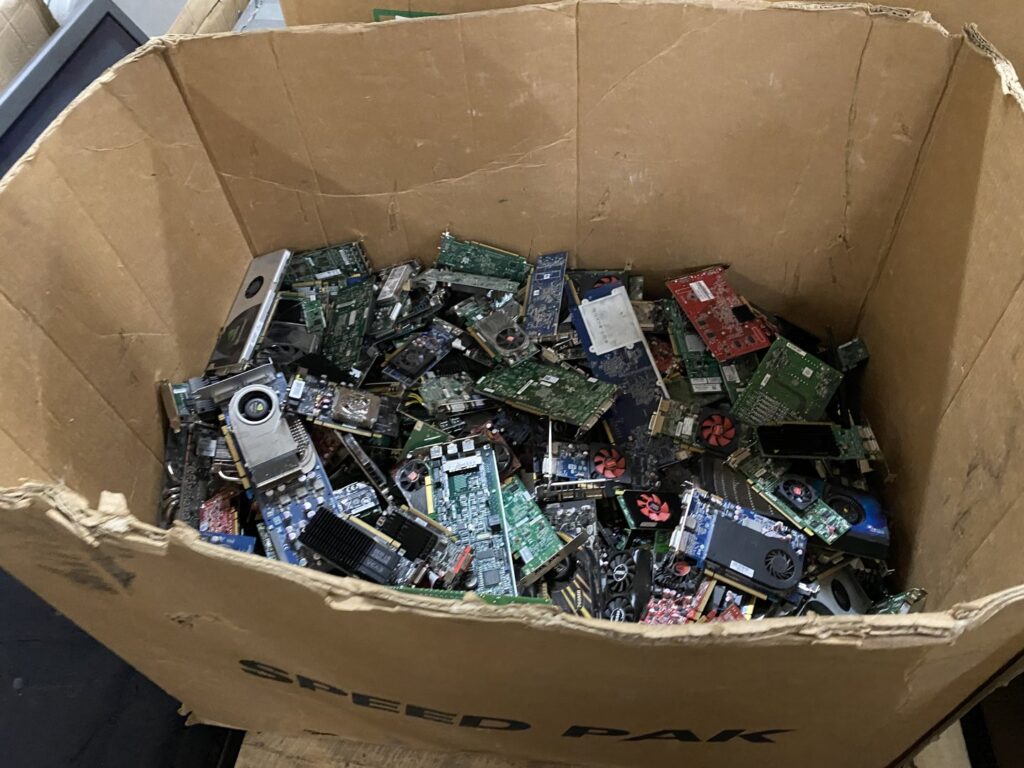 A large cardboard box filled with various computer components and circuit boards for recycling at R3Ewaste in Phoenix, AZ