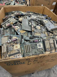 A cardboard box overflowing with computer motherboards and other e-waste at E-Z Money Recycling LLC in Phoenix, AZ.