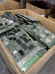 A box filled with large circuit boards and electronic components ready for recycling at E-Z Money Recycling LLC in Phoenix, AZ.