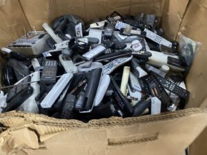 A box filled with various remote controls, collected as e-waste by R3Ewaste in Phoenix, AZ