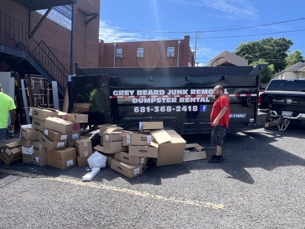 Cardboard boxes piled next to a Greybeard Dumpster Rentals trailer, ready for junk removal in Morgantown, WV.
