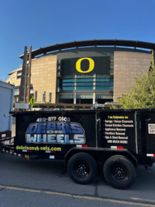 A branded black dump trailer from Debris On Wheels, listing junk removal services in Eugene, OR.