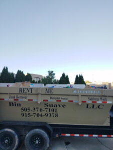 A Bin Suave LLC branded dump trailer advertising junk removal and dumpster rentals in Espanola, NM.
