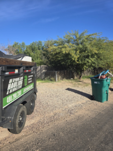 A branded junk removal trailer from ALL around junk, LCC parked on a gravel lot in Mesa, AZ, ready for a job.