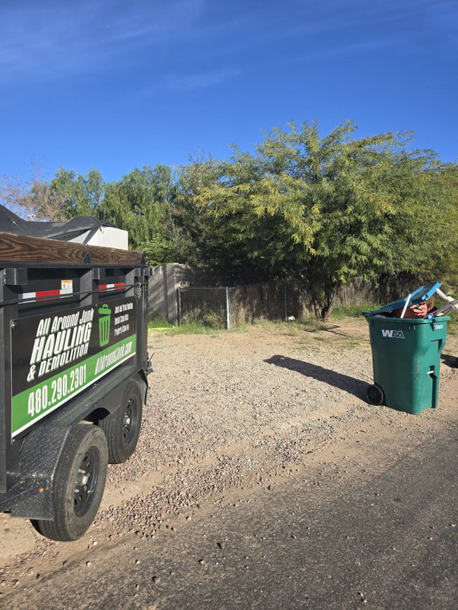 A branded junk removal trailer from ALL around junk, LCC parked on a gravel lot in Mesa, AZ, ready for a job.