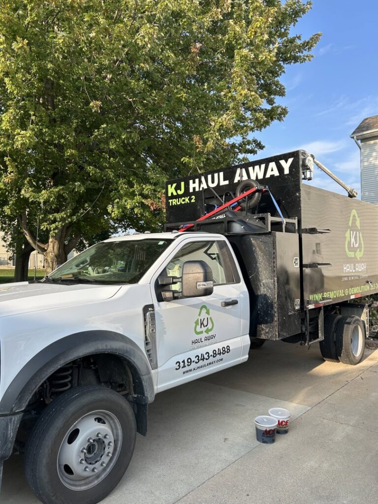 A branded KJ Haul Away Junk Removal truck, 'Truck 2', parked on a driveway in Cedar Rapids, IA, ready for service.
