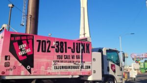 A branded pink junk removal truck from Las Vegas Hauling Junk & Moving on a street in Las Vegas, NV