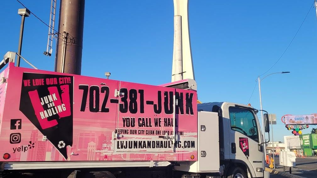 A branded pink junk removal truck from Las Vegas Hauling Junk & Moving on a street in Las Vegas, NV