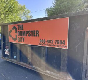 A close-up of a branded roll-off dumpster from The Dumpster Guy, used for junk removal services in Webster, MA.