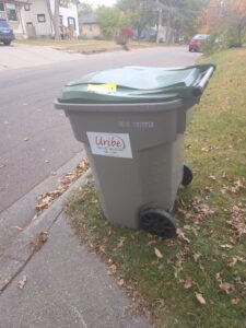 A Uribe Refuse Services branded trash can placed curbside on a residential street in Lincoln, NE.