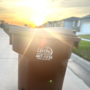 A Uribe Refuse Services branded trash can on a residential street at sunset in Lincoln, NE.