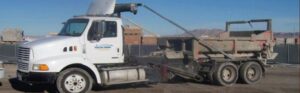A branded waste hauler truck with a large container from A Track-Out Solution, ready for service in Las Vegas, NV.