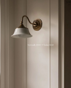 A classic brass and white wall sconce mounted on a paneled wall, demonstrating lighting installation by Wiersma Homes in Knoxville, TN.