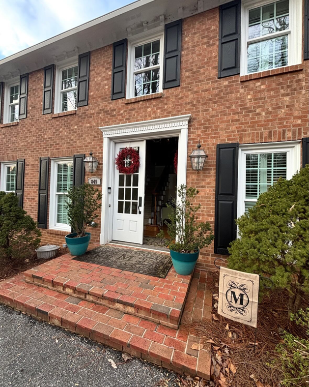 The exterior of a classic brick house with black shutters and a welcoming front door by Welcome Home Building Services in Winston-Salem, NC.