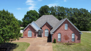 An aerial view of a brick residential house featuring a newly installed gray shingle roof by Northcross Restoration Inc in Memphis, TN.