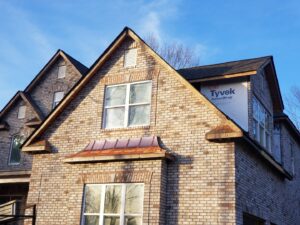 Brick house exterior with new windows and a decorative copper awning by American Custom Exteriors in North Charleston, SC.