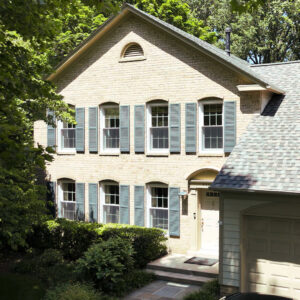 A brick house with newly installed windows and shutters, showcasing exterior home improvement by Four Seasons Home Improvement Company, Inc. in Rockville, MD.