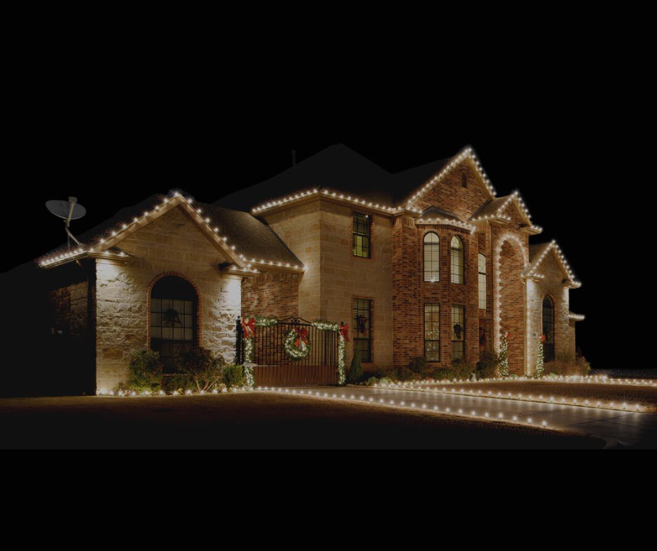 A large brick house with elegant white lights installed on the roofline and outlining the driveway by Lights Made Easy of Charleston, SC