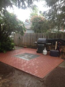 A newly constructed brick patio with a grill area in a backyard by Ground Up Services in Anchorage, AK.