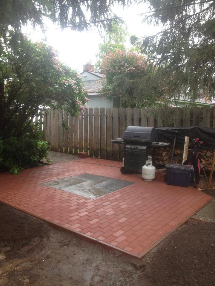 A newly constructed brick patio with a grill area in a backyard by Ground Up Services in Anchorage, AK.