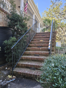 Newly installed black metal railings on brick stairs leading to a home, a service by Lowcountry Current LLC in Moncks Corner, SC.