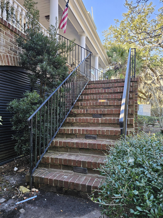 Newly installed black metal railings on brick stairs leading to a home, a service by Lowcountry Current LLC in Moncks Corner, SC.