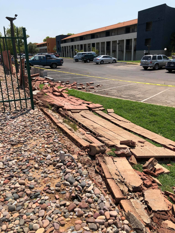Extensive damage to a brick wall with debris and caution tape, handled by Ken's Masonry, LLC in Chandler, AZ.
