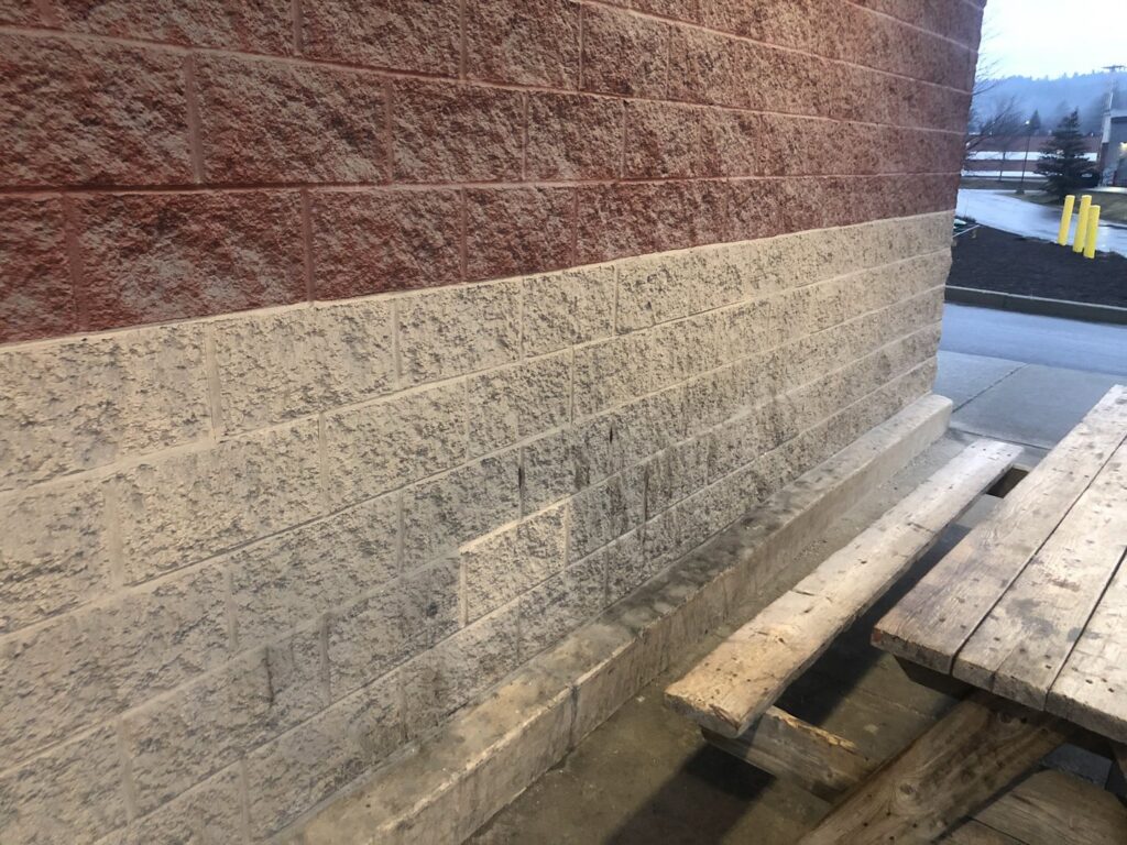 A brick wall showing a clean lower section and dirty upper section, indicating power washing by Phoenix's Cleaning Service, LLC in Rutland, VT.