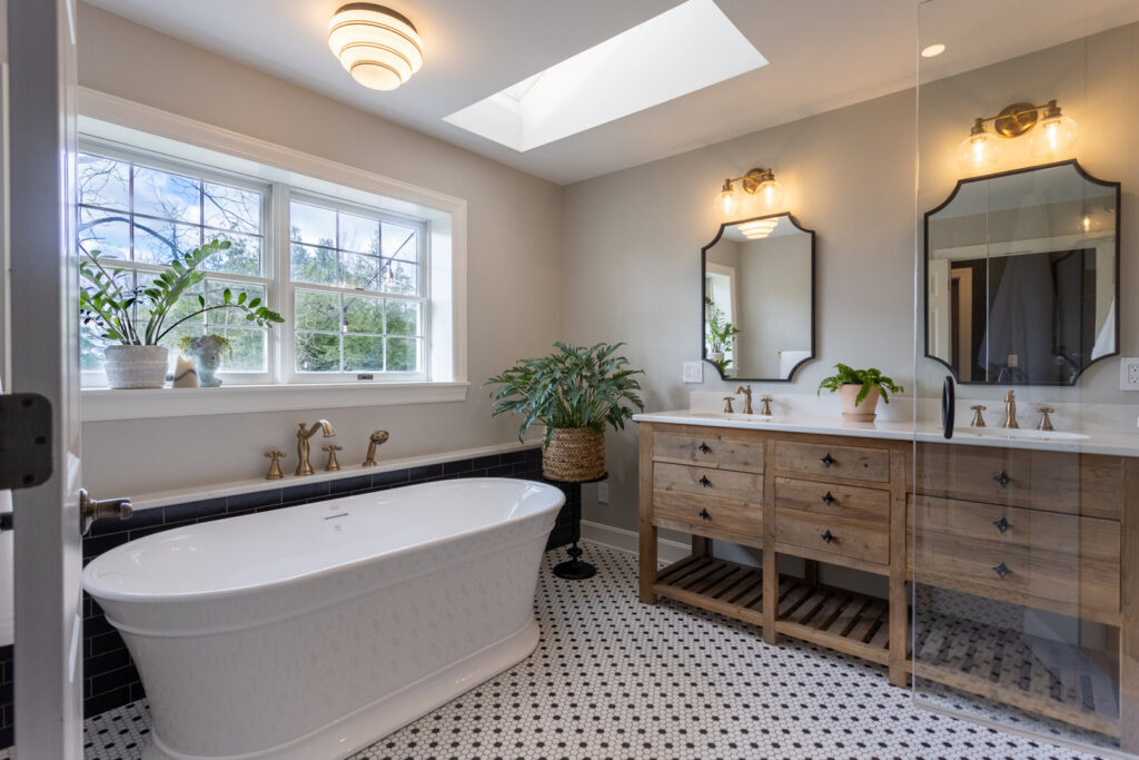 A bright bathroom renovation featuring a freestanding tub, double vanity, and classic black and white floor tiles by Legacy Builders Group in Cincinnati, OH.