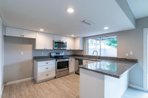 A bright kitchen showcasing new granite countertops and white cabinets installed by L&M Granite Countertops in Phoenix, AZ.