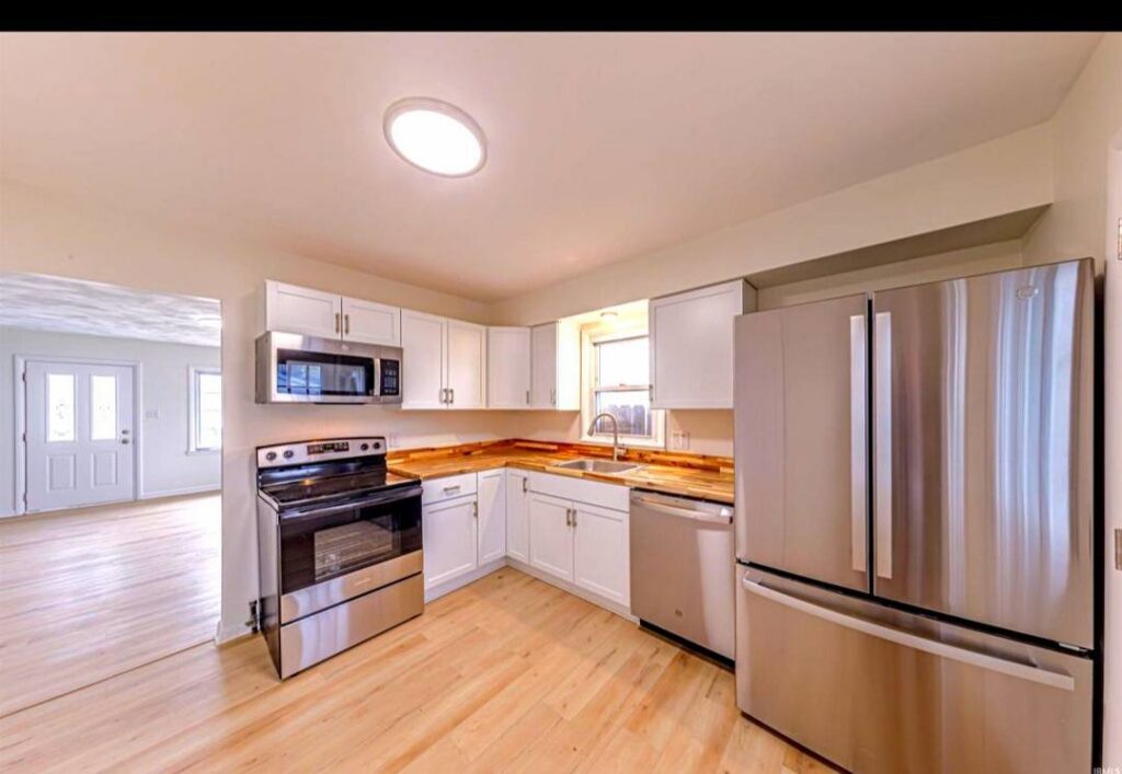 A bright kitchen renovation with white cabinets, wood countertops, and new appliances by Imperial Access Contracting in Evansville, IN.