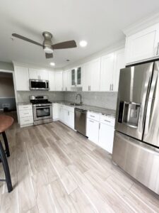 A bright kitchen renovation showcasing white cabinets, stainless steel appliances, and new wood-look flooring by RW Contracting Phila, LLC in Philadelphia, PA.