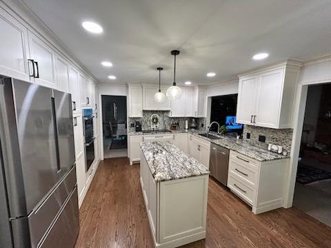 A bright, modern kitchen with white cabinets, granite countertops, and a large island by Creative Building & Remodeling in Warren, MI