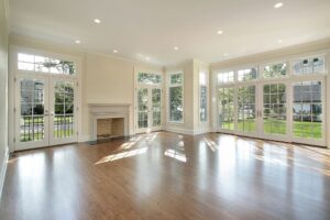 A bright living room with numerous windows, hardwood floors, and a stone fireplace, showcasing handyman services by Paradise Found Construction in Cary, NC.