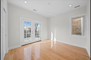 A bright, renovated room with hardwood floors and French doors leading to a balcony by Revival Home Remodeling in Chicago, IL.