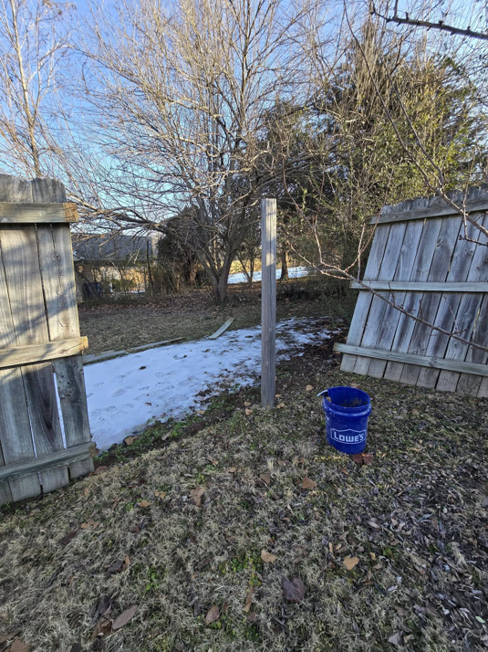 A broken wooden fence with a single post standing, indicating fence repair preparation by Creekside Handyman NWA in Centerton, AR.